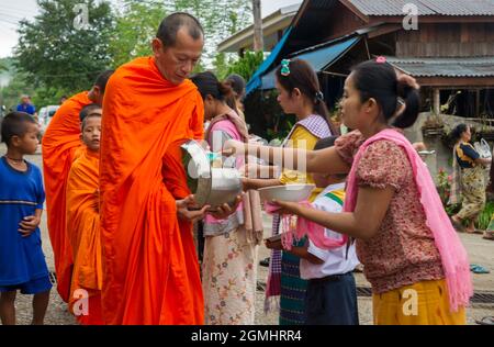 THAILANDIA, SANGKHLA BURI - 21 NOVEMBRE 2012: Monaci buddisti che raccolgono elemosina e cibo dato dalla popolazione locale al mattino presto il loro alm quotidiano Foto Stock