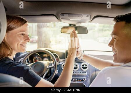 Una donna acquista un'auto o prende un'auto in affitto, forse un ragazzo asiatico ha dato un'auto, una stretta di mano in auto, risate e gioia. Foto Stock