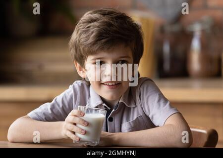 Sorridente ragazzino carino che beve yogurt biologico. Foto Stock