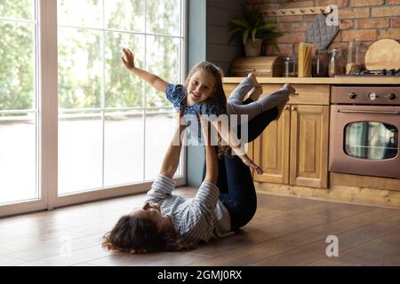 Cura giovane madre felice sollevamento in aria carino bambino figlia. Foto Stock