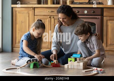 Felice madre giovane che gioca i giocattoli con i bambini carini. Foto Stock