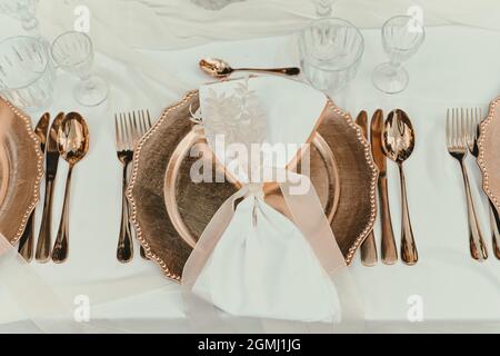 Bellissimi piatti dorati sul tavolo il giorno del matrimonio. Decorazione per feste, matrimoni e compleanni Foto Stock