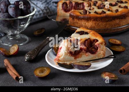 Torta di cagliata francese con prugne, pronta a mangiare su un piatto su un tavolo grigio. Primo piano Foto Stock