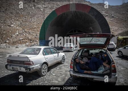 Passo di Salang, Afghanistan. 19 Settembre 2021. Un uomo afghano riposa nel bagagliaio di un'auto mentre altri veicoli entrano nel tunnel di Salang attraversando l'Hindu Kush sul Passo di Salang, il passo di montagna primario che collega l'Afghanistan settentrionale con la Provincia di Parwan, con collegamenti in avanti con la Provincia di Kabul. Credit: Oliver Weiken/dpa/Alamy Live News Foto Stock