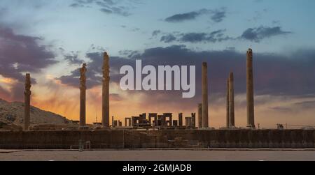 Rovine di Apadana e Palazzo Tachara dietro la scalinata con intagli a bassorilievo in Persepolis Sito Patrimonio dell'Umanità dell'UNESCO contro il cielo nuvoloso del tramonto a Shi Foto Stock