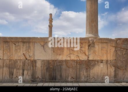 Rovine di Apadana e Palazzo di Tachara dietro la scalinata con sculture a bassorilievo in Persepolis, patrimonio dell'umanità dell'UNESCO, contro il cielo blu nuvoloso di Shira Foto Stock