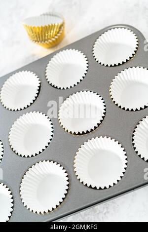 Foderare la teglia per cupcake con i fodere per preparare i cupcake di s'mers. Foto Stock