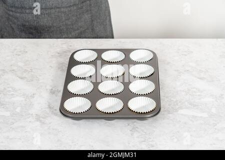 Foderare la teglia per cupcake con i fodere per preparare i cupcake di s'mers. Foto Stock