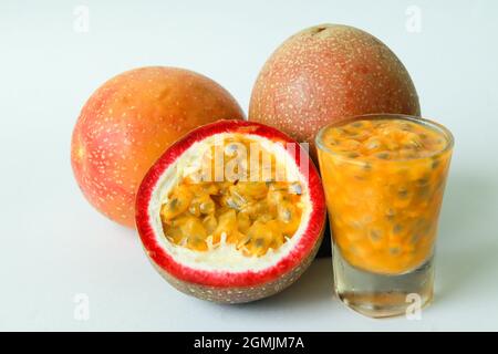 Frutto della passione su sfondo bianco con frutta intera, metà e succo di frutto della passione in un bicchiere. Spazio di copia. Foto Stock