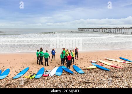 Scuola di surf con istruttore, alunni e tavole da surf sulla spiaggia a Saltburn by the Sea, Redcar e Cleveland District, North Yorkshire, Inghilterra, Foto Stock