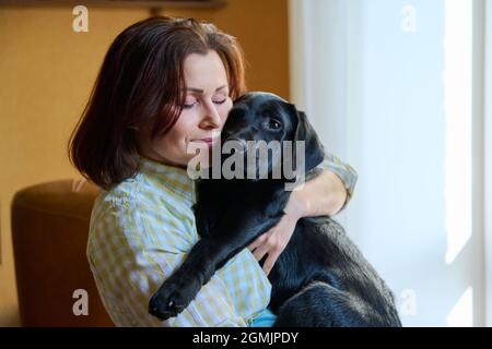 Ritratto di donna di mezza età e nero labrador cucciolo cane Foto Stock