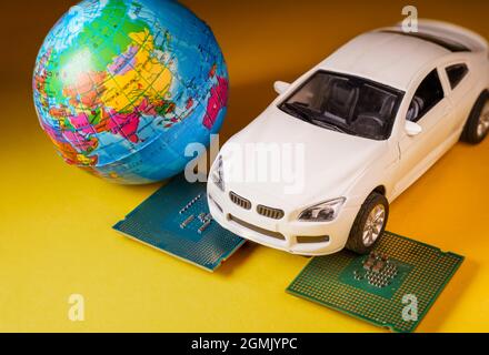 Vista ravvicinata di un'auto giocattolo bianca sopra un microprocessore e un mondo. Foto Stock