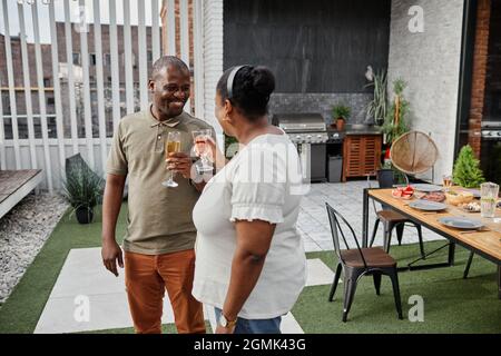 Ritratto di coppia afro-americana adulta godendo di bevande sulla terrazza all'aperto e sorridendo felicemente, spazio copia Foto Stock