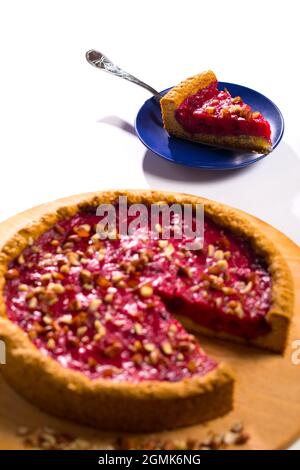 Torta di frutta dolce con arachidi e su un oculare tagliato su un piatto, su sfondo bianco. Foto Stock