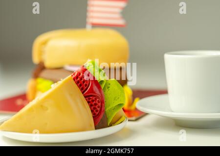 Pezzo della torta Burger, Madeira e torta stratificata di spugna di cioccolato, riempito con glassa ricoperta di glassa morbida e decorazioni di zucchero commestibile, torta i Foto Stock