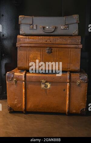 Fuoco selettivo su mucchio di tre valige vintage, vecchie e avvertono di viaggio o tronchi sul pavimento. Viaggio in stile retrò. Foto Stock