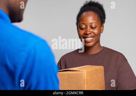 signora africana che riceve un pacchetto da un lavoratore di consegna Foto Stock