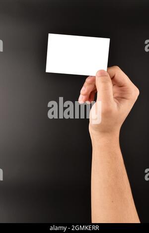 mano che mostra il biglietto da visita vuoto su sfondo scuro Foto Stock