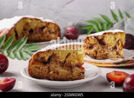 Torta di prugne fatta in casa con pezzi tagliati su un piatto su uno sfondo chiaro primo piano. Foto Stock