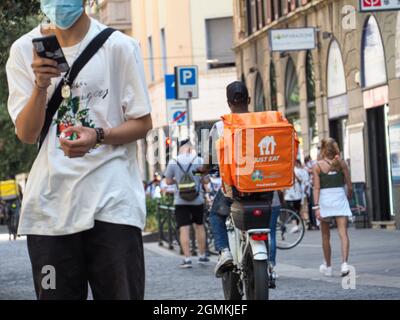 MILANO, ITALIA - 08 ago 2021: Primo piano di un corriere con un sacchetto arancione che consegna cibo con una bicicletta, Milano, Italia Foto Stock