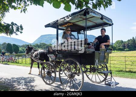Corsa in carrozza a cavallo di famiglia alla casa di Muckross 19 ° secolo, il Parco Nazionale, Killarney (Cill Airne), County Kerry, Repubblica d'Irlanda Foto Stock