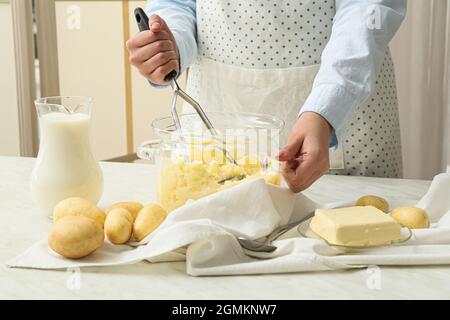 Donna che prepara gustose purè di patate sul tavolo in cucina, primo piano Foto Stock