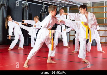 Ragazzi che lavorano in coppia, padroneggiare i calci in classe karate Foto Stock