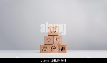 Strategia aziendale con processo di successo della crescita per il concetto di leadership e lavoro di squadra. Il piano d'azione, l'icona del bersaglio di affari sui blocchi di cubo di legno sta Foto Stock