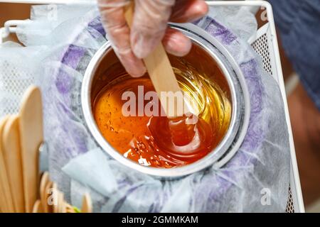 Foto di cera di miele fusa su bastone di legno per depilazione Foto Stock