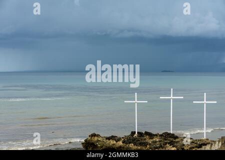 Si avvicina alla tempesta di tuono dietro tre croci bianche sulla spiaggia di Ketapang Satu nella città di Kupang, Timor Ovest, Indonesia. Foto Stock