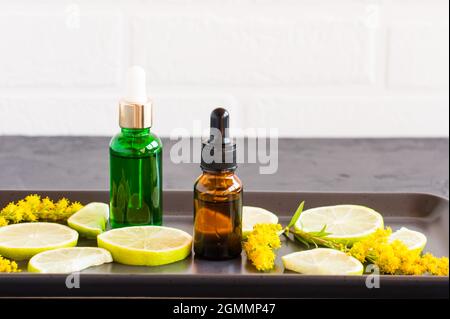 due bottiglie con pipetta con prodotto cosmetico in limone e lime per la cura del viso e del corpo. cosmetici di natura naturale Foto Stock