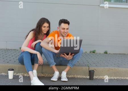 Giovane coppia che usa il portatile sul marciapiede Foto Stock