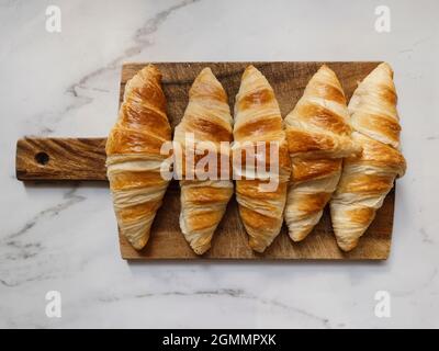 Vista dall'alto sui croissant freschi sul tagliere di legno Foto Stock