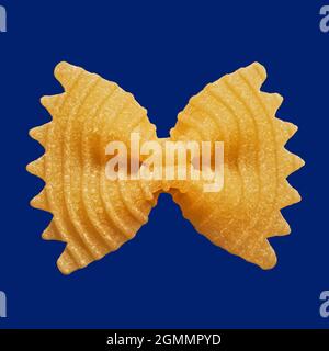 Primo piano su spaghetti di farfalle bowtie non cotti su sfondo blu Foto Stock