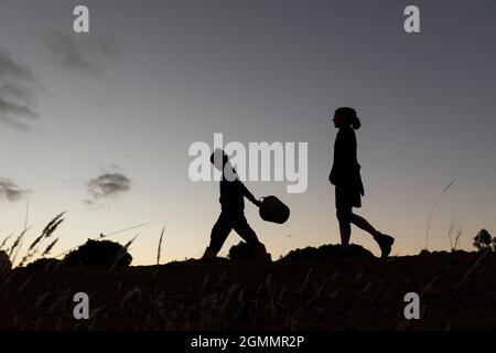 Silhouette madre e figlio che cammina contro il cielo crepuscolo Foto Stock