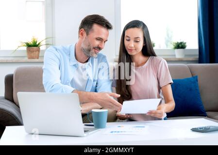 Coppia felice calcolando i soldi a casa. Revisione finanziaria, concetto di bilancio domestico Foto Stock