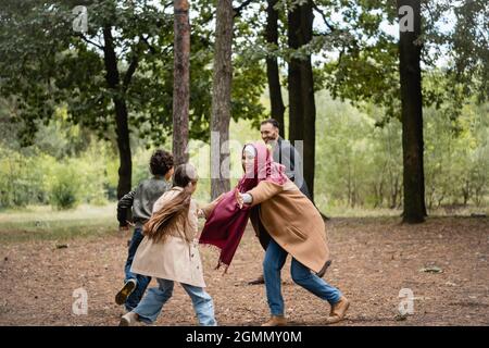 Madre musulmana che gioca con la figlia vicino alla famiglia nel parco Foto Stock