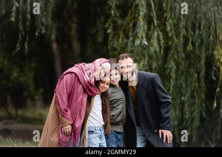 I genitori arabi sorridono alla macchina fotografica vicino ai bambini nel parco Foto Stock