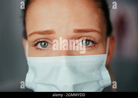 Infermiere trainee caucasico in piedi in ufficio medici indossare maschera Foto Stock