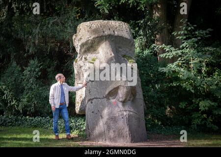 PRODUZIONE - 14 Settembre 2021, Hessen, Francoforte sul meno: Jens Söring si trova accanto a una riproduzione gigante di una scultura Moai nel Palmengarten di Francoforte. Il figlio di un diplomatico tedesco è stato condannato a vita in prigione negli Stati Uniti per il doppio omicidio e fu deportato in Germania solo nel 2019 dopo 33 anni di ritardo nei bar. Qui sta ora cercando di costruire una nuova esistenza. (Al dpa 'dopo più di 33 anni di carcere: I primi mesi di Jens Söring in libertà') Foto: Boris Roessler/dpa Foto Stock