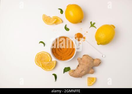 Ingredienti freschi a fette di curcuma, zenzero e limone acido su sfondo bianco. Bevanda vitaminica naturale che protegge la salute dai virus. Foto Stock