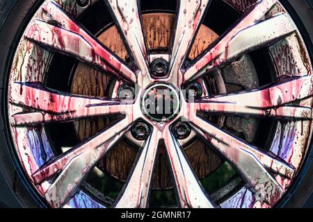 Processo di pulizia delle ruote dell'auto. Il detergente per cerchioni produce una reazione chimica viola quando si rimuovono inclusioni di metallo o ferro e polvere dei freni. Dettaglio lavaggio auto. Foto Stock