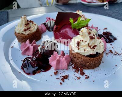 Primo piano di un piatto bianco di dessert assortiti sul tavolo Foto Stock