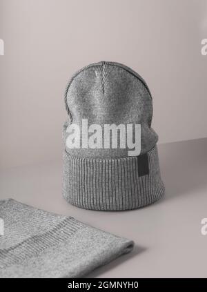 Cappello in maglia grigio piccolo con fondo bianco sciarpa jn grigio. Cappellino in lana. Spazio di copia Foto Stock