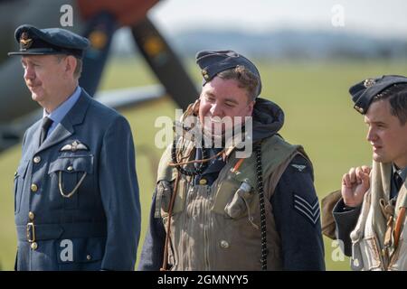 IWM Duxford, Cambridgeshire, Regno Unito. 18 settembre 2021. Primo giorno della Battaglia di Gran Bretagna Air Show a IWM Duxford, l'ex sito RAF che ha svolto un ruolo centrale come base per molti dei piloti Spitfire e uragano durante la seconda guerra mondiale. Le grandi folle guardano il re-enattore equipaggio di volo a piedi oltre una fila di Spitfire parcheggiati. Credit: Malcolm Park/Alamy Foto Stock