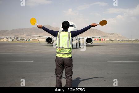 Kabul, Afghanistan. 20 Settembre 2021. Un membro dell'equipaggio di terra dà segnali al pilota di un aereo all'aeroporto internazionale di Kabul a Kabul, capitale dell'Afghanistan, 20 settembre 2021. Sono in corso sforzi per risolvere tutte le difficoltà tecniche prima che i voli commerciali internazionali riprendano all'aeroporto internazionale di Kabul, ha detto lunedì il direttore dell'aeroporto Abdul Hadi Hamadani. Credit: Saifurahman Safi/Xinhua/Alamy Live News Foto Stock