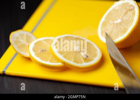 Limone affettato sul tagliere giallo e coltello accanto ad esso Foto Stock