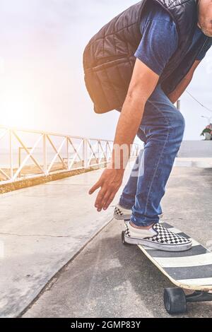 Il modo perfetto per attraversare queste strade, adolescente in abiti da strada si alza con una tavola lunga, guarda la macchina fotografica e sorride. Cultura di strada. Foto Stock