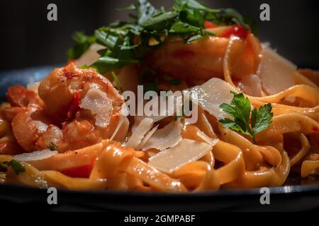 Scampi di gamberi un classico della cucina italiana. Gamberi e linguine in una salsa barbecue al limone, burro, aglio. Linguine con pomodori, verdure e gamberi. Foto Stock