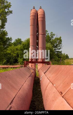 Acqua calda - tubi di vapore con ponte nella natura estiva Foto Stock